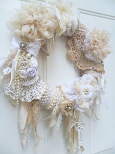 a wreath made out of lace and fabric with flowers on the front door, attached to a white door