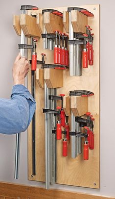 a man is working on a wall mounted tool rack with tools attached to the pegs