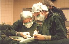 two surgeons are performing surgery in an operating room with surgical equipment on their hands and one surgeon is holding scissors