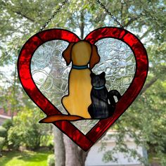 a stained glass window with a dog and cat in the heart shaped frame hanging from a chain