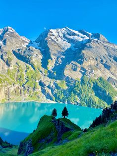 the mountains are covered in snow and green grass, as well as some blue water