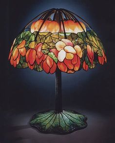 a lamp that is on top of a green base with flowers and leaves painted on it