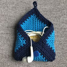 a blue and white crocheted bag with earphones in it