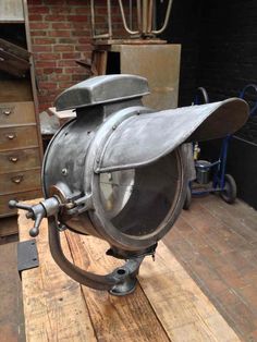 an old fashioned metal object sitting on top of a wooden table next to a brick wall