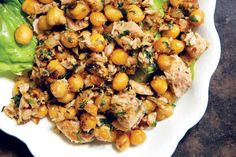 a white plate topped with chickpeas and lettuce on top of a table