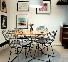 a dining room table with chairs and pictures on the wall in front of it,