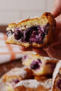 a person holding up a pastry with blueberries on it