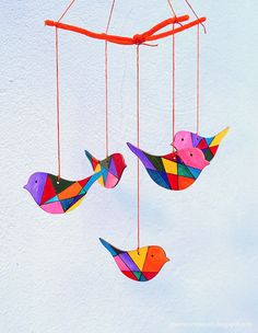 three colorful birds hanging from strings in the snow