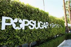 a sign that says popsup on the side of a wall covered in green plants