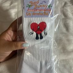 someone's hand holding up a pair of white socks with red heart on it