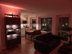 a living room filled with furniture next to a window covered in pink lights at night