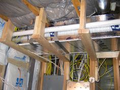 an unfinished room with wires and duct tape on the ceiling, and electrical wiring attached to the wall