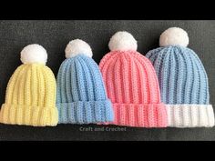 three knitted hats with pom poms on them, all in different colors