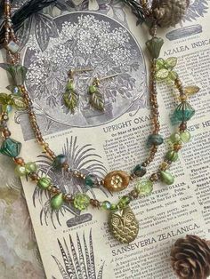 Step into a world of natural wonder with our enchanting Vintage Botanical Owl Necklace and matching earrings set! 🦉🍃 Handcrafted with love, this unique ensemble features: * Genuine Czech glass beads in soothing green and warm gold tones * Delicate leaf charms that whisper tales of forest mysteries * A charming owl pendant, guardian of ancient wisdom * Intricate botanical-inspired elements throughout Perfect for: * Nature enthusiasts and woodland creature lovers * Vintage and boho style aficion Czech Glass Necklace, Jewelry Nature, Owl Necklace, Owl Pendant, Nature Inspired Jewelry, Leaf Charms, Beaded Material, Vintage Botanical, Glass Necklace