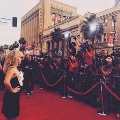 a woman is standing on the red carpet in front of photographers and papa's