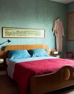 a bed in a bedroom with blue walls and red bedspread on top of it