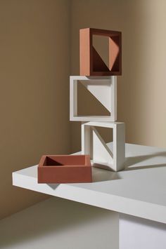 three different colored boxes sitting on top of a white table in front of a brown wall