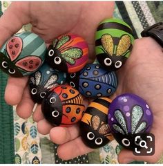 a person holding several colorful painted rocks in their hand