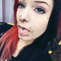 a woman with red hair and piercings on her nose is making a funny face