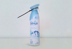 a blue bottle that is sitting on a table next to a wall with the words febreze written in it