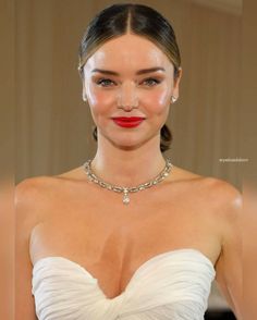 a woman in a strapless white dress wearing a necklace and red lipstick on her lips