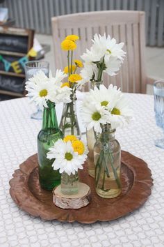 three vases filled with flowers sitting on top of a wooden tray next to each other