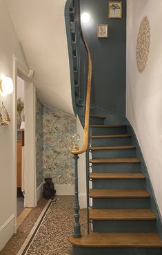 a long wooden stair case next to a wall with pictures on it and a light hanging from the ceiling