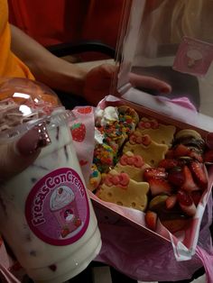 there is a box of cookies and strawberries next to a cup of milkshake