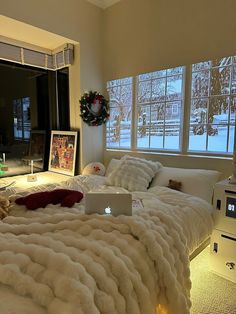 a laptop computer sitting on top of a bed in a bedroom next to a window