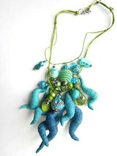 a necklace with blue and green beads hanging from it's side on a white surface