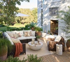 an outdoor living area with wicker furniture and potted plants