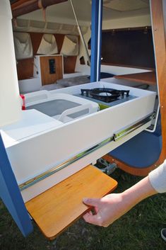 a person holding a piece of wood in front of a white boat with blue trim