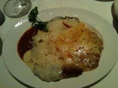 a white plate topped with meat covered in sauce and gravy on top of a table