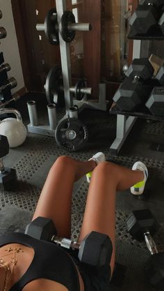 a woman laying on the ground in front of a gym machine with dumbbells