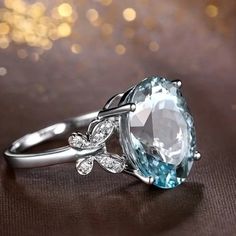 an oval blue topazte and diamond ring on a brown surface with lights in the background