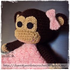 a crocheted stuffed monkey wearing a pink and brown dress with big eyes sitting on top of a table