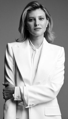 a black and white photo of a woman in a suit with her arms folded out