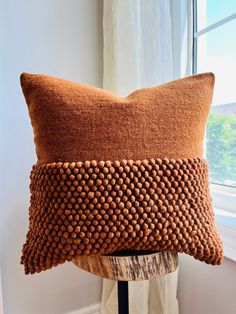 a brown pillow sitting on top of a wooden table next to a white window sill