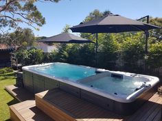 a hot tub sitting on top of a wooden deck next to an umbrella over it