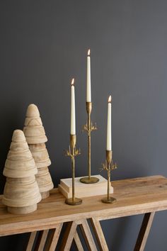 three candles sitting on top of a wooden table next to stacks of stacked wood logs