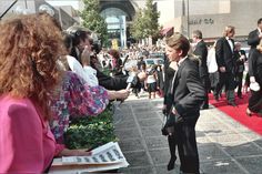 a man in a suit shaking hands with a woman on a red carpet