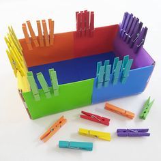 several colorful office supplies are arranged in a box with clips and paper clip holders on the sides