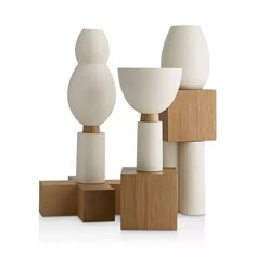 three white vases sitting on top of wooden blocks