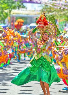 a woman in a green dress and headdress walking down the street with other people