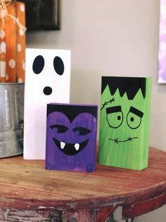 three wooden blocks with faces painted on them sitting on a table next to a canister