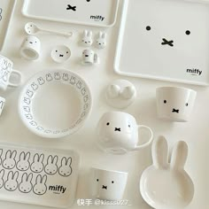 a table topped with white dishes and bunny shaped plates, cups and spoons next to each other