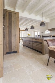 an open kitchen and dining area with wooden cabinets, marble flooring and pendant lights