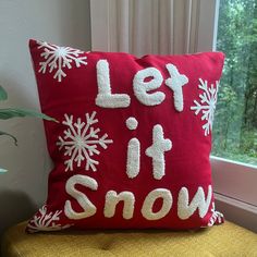 a red pillow that says let it snow