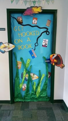 a door decorated with paper fish and words that read, get hooked on a book