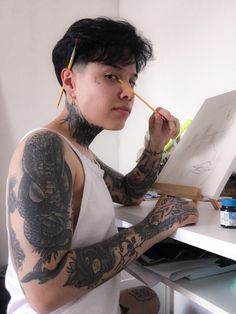 a woman with tattoos holding a pencil and drawing